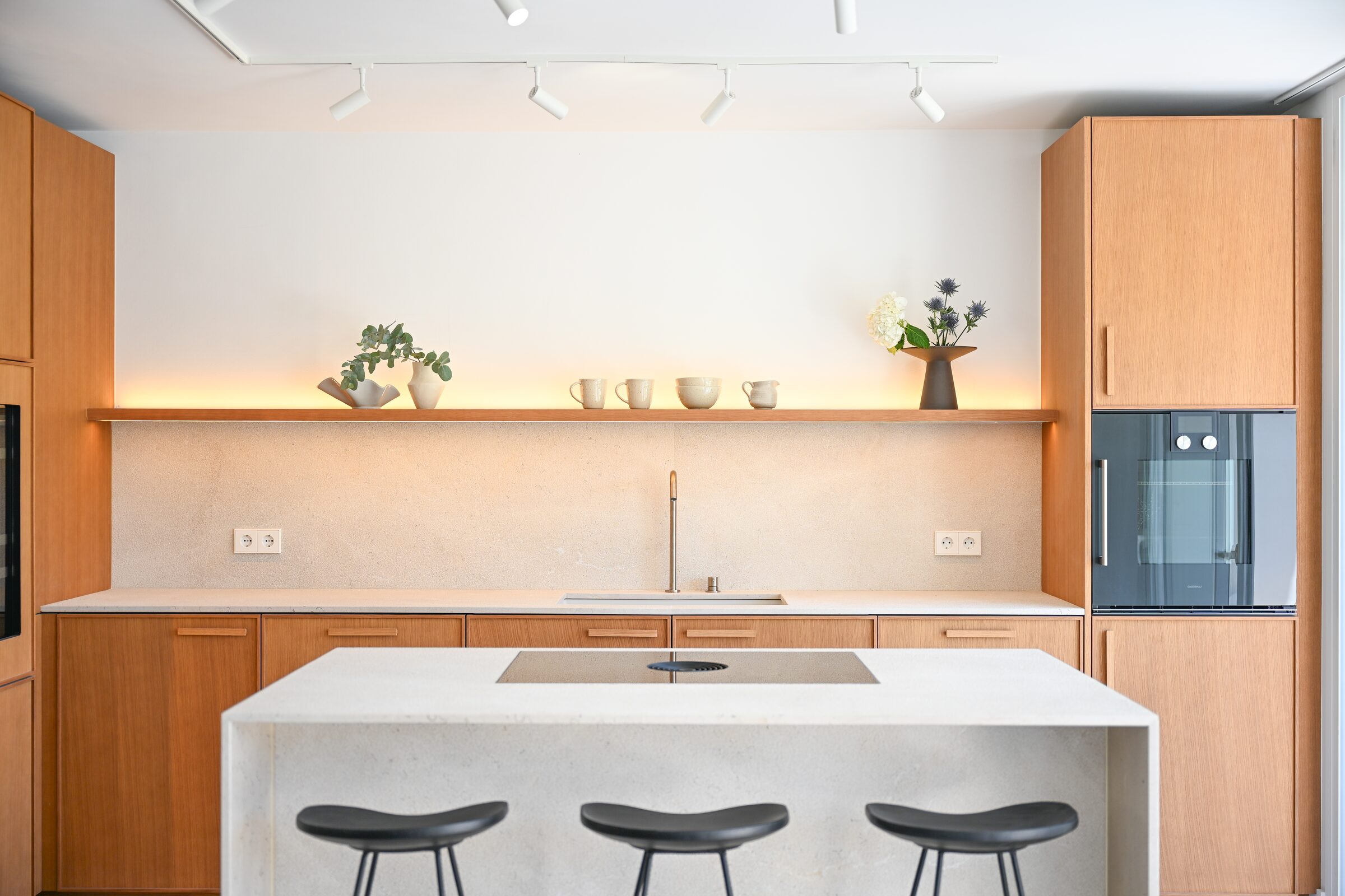 Open-plan living, dining and oak kitchen with sculpted concrete staircase and Zarci stone floors.