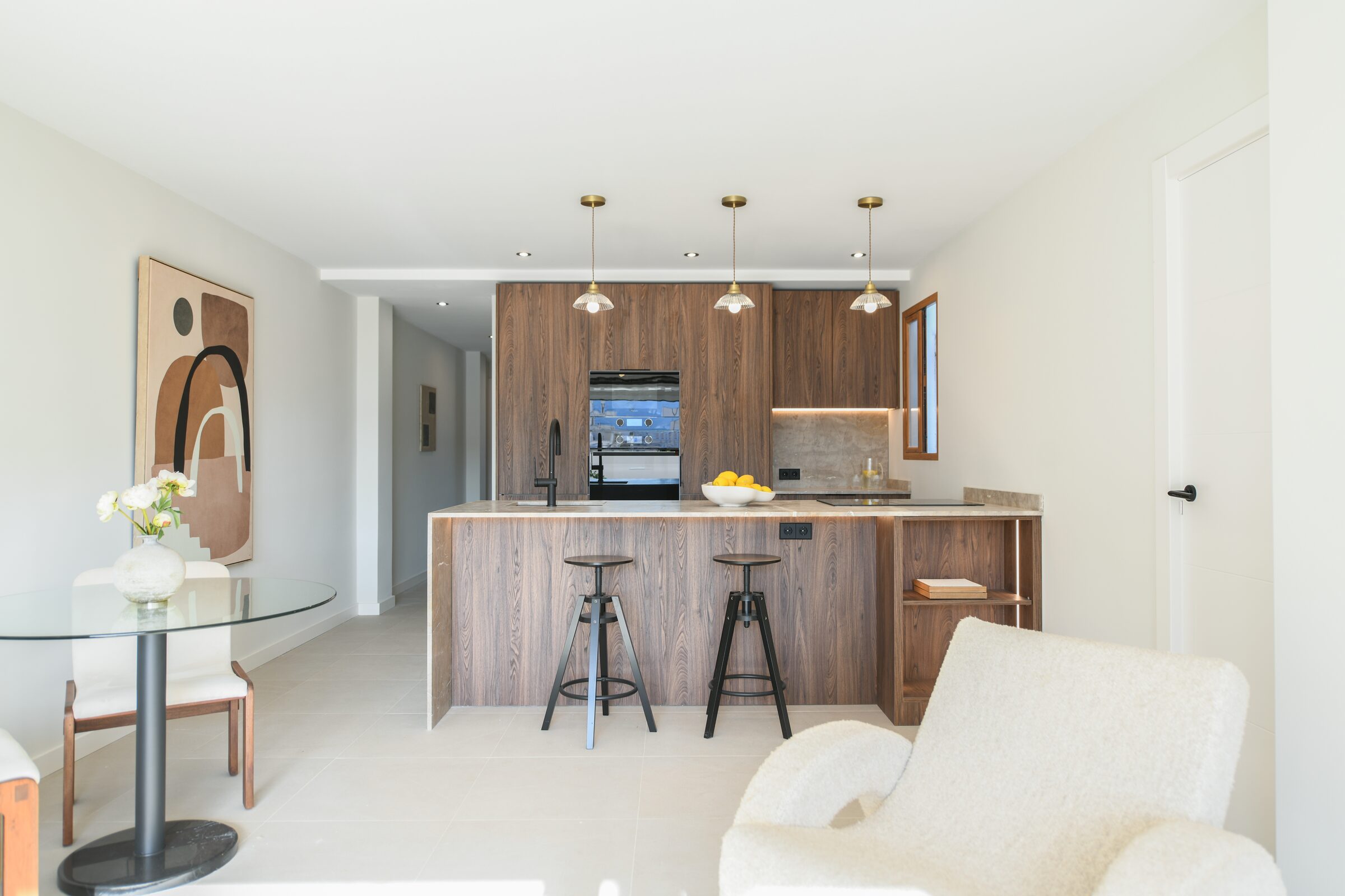 Open kitchen with walnut cabinetry and a travertine island in the Despuig penthouse.