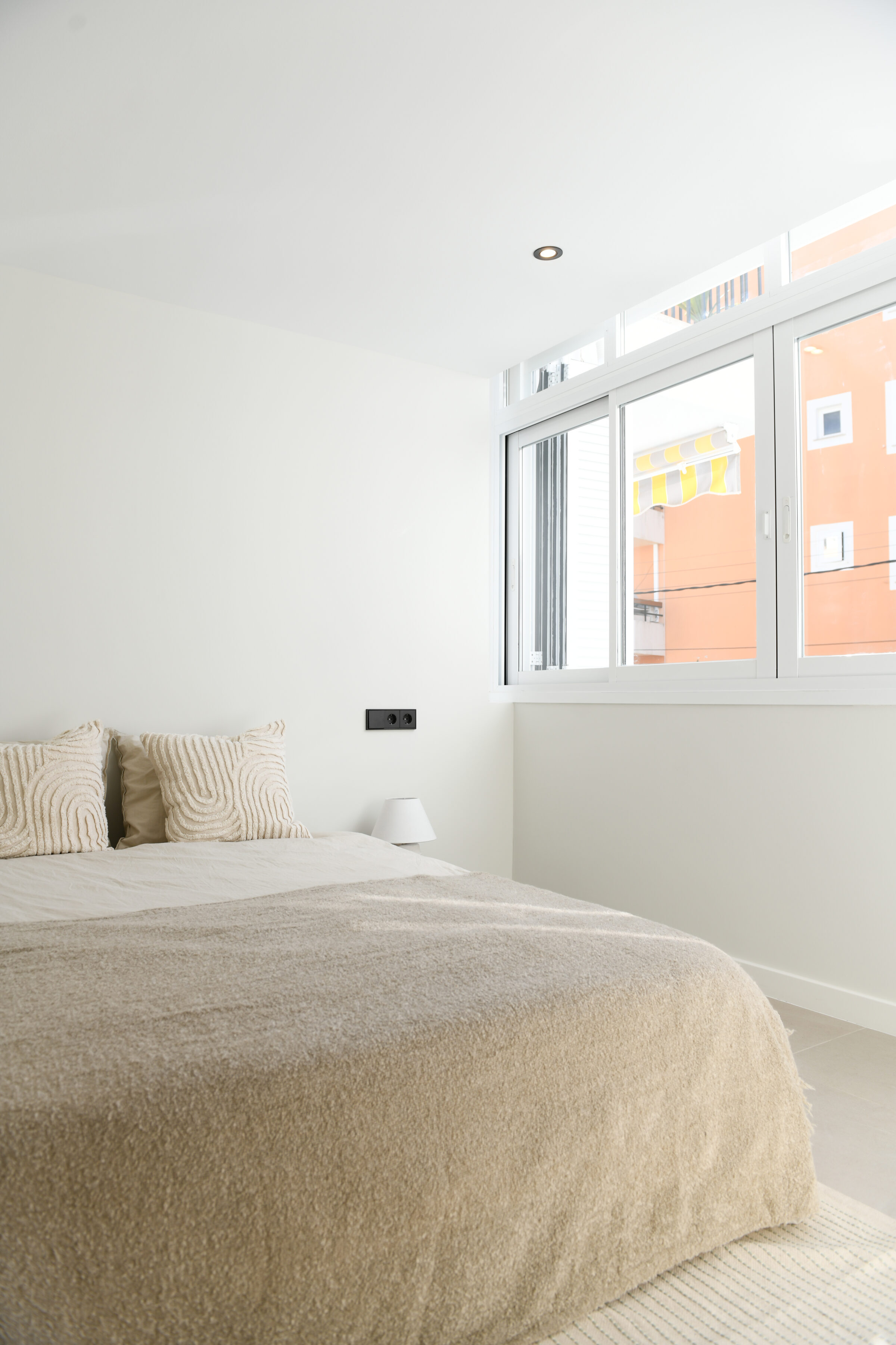 Third bedroom with ribbed linen bedding and morning light through the window.