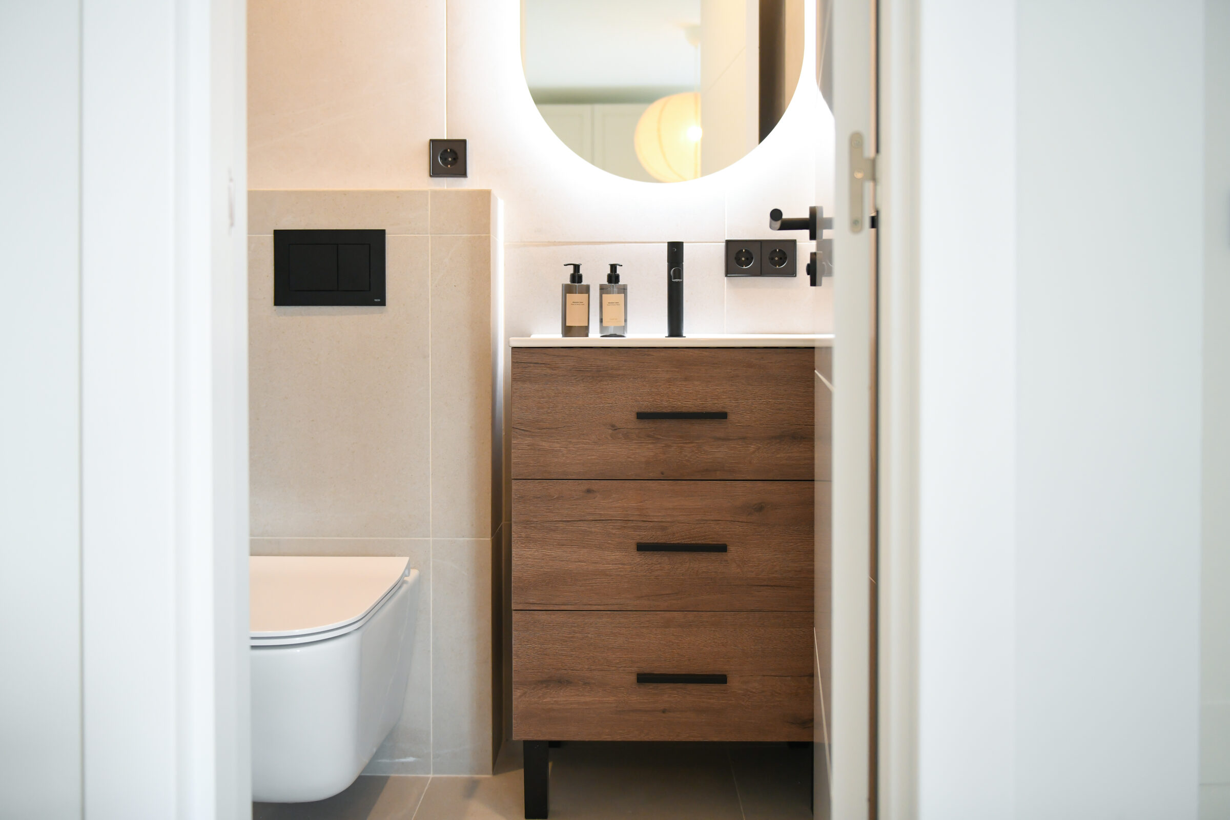 Guest powder room finished in beige stone with a walnut vanity.