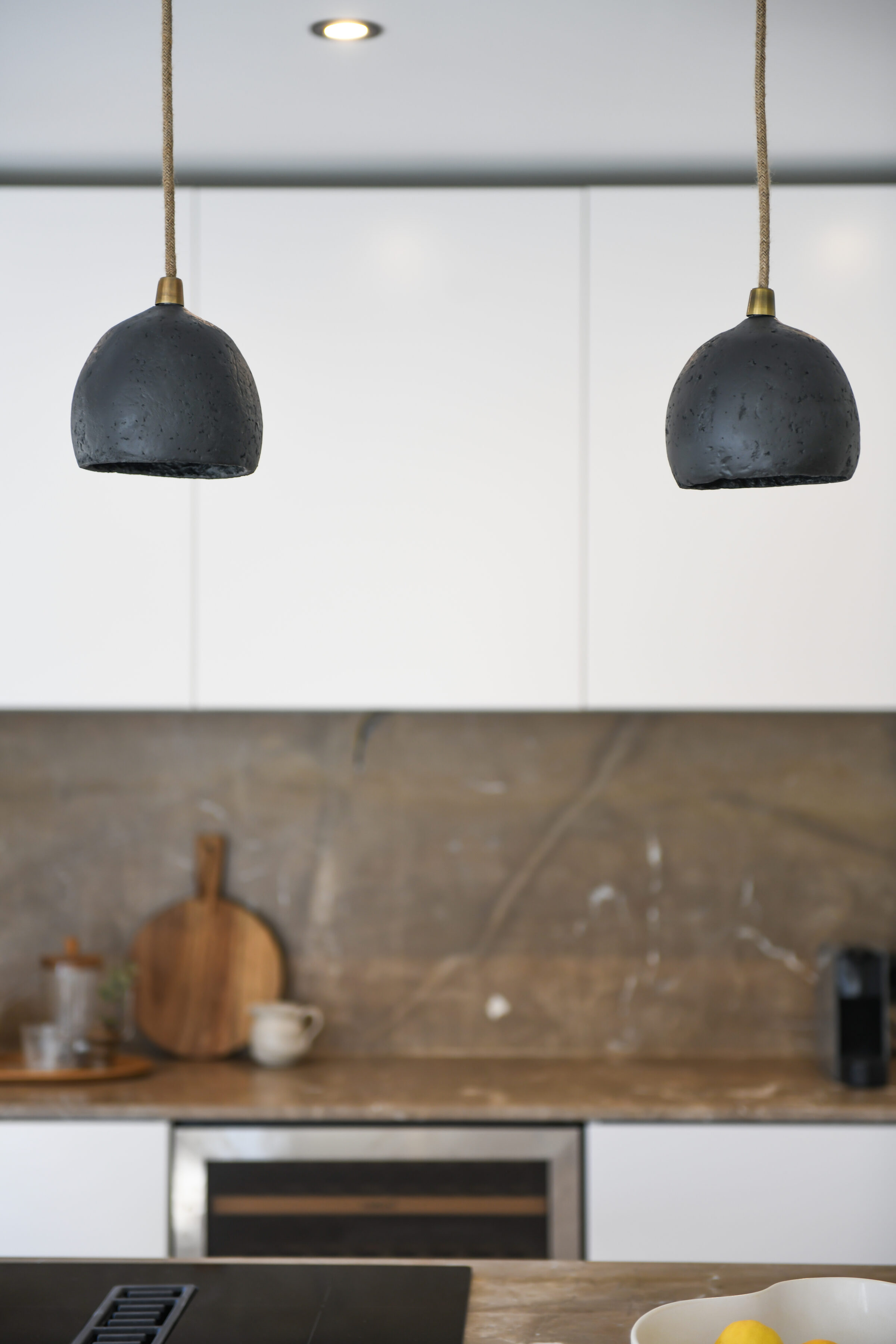 Detail of black ceramic pendant lights above the marble kitchen island.