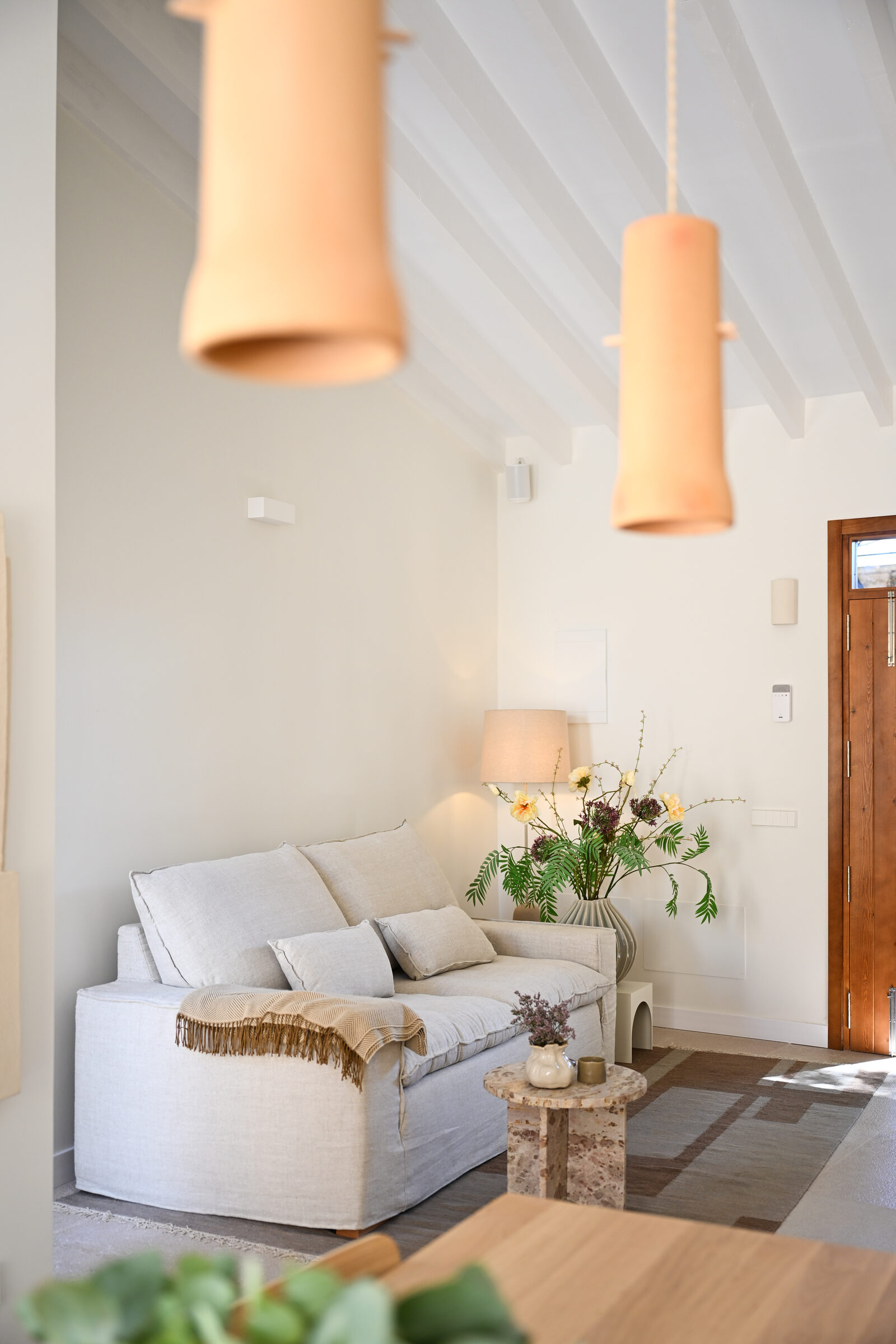 Living corner with terracotta-toned ceramic pendants and a vaulted white ceiling.