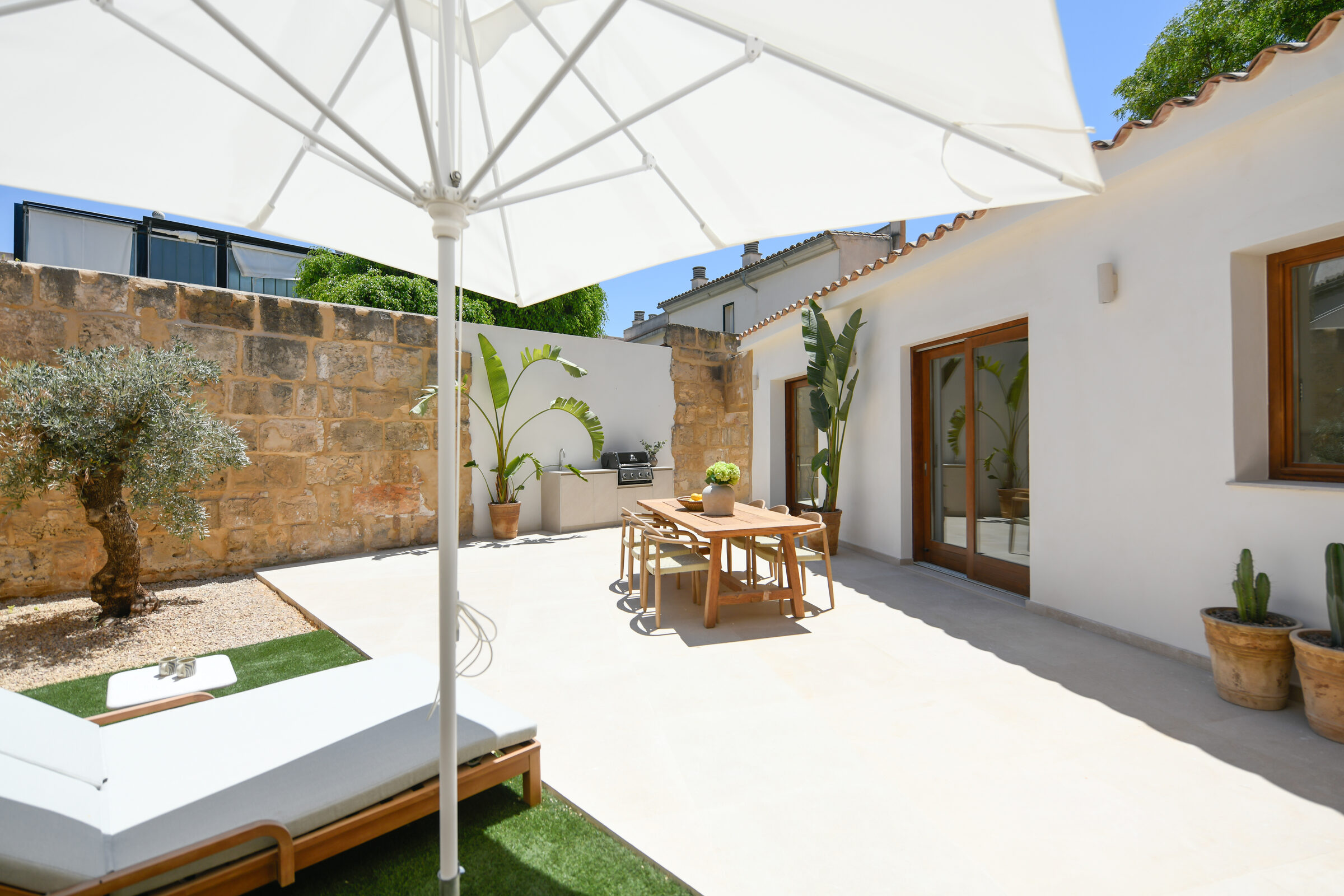 Private 90 m² south-facing garden with original marès stone walls, parasol and sun lounger.