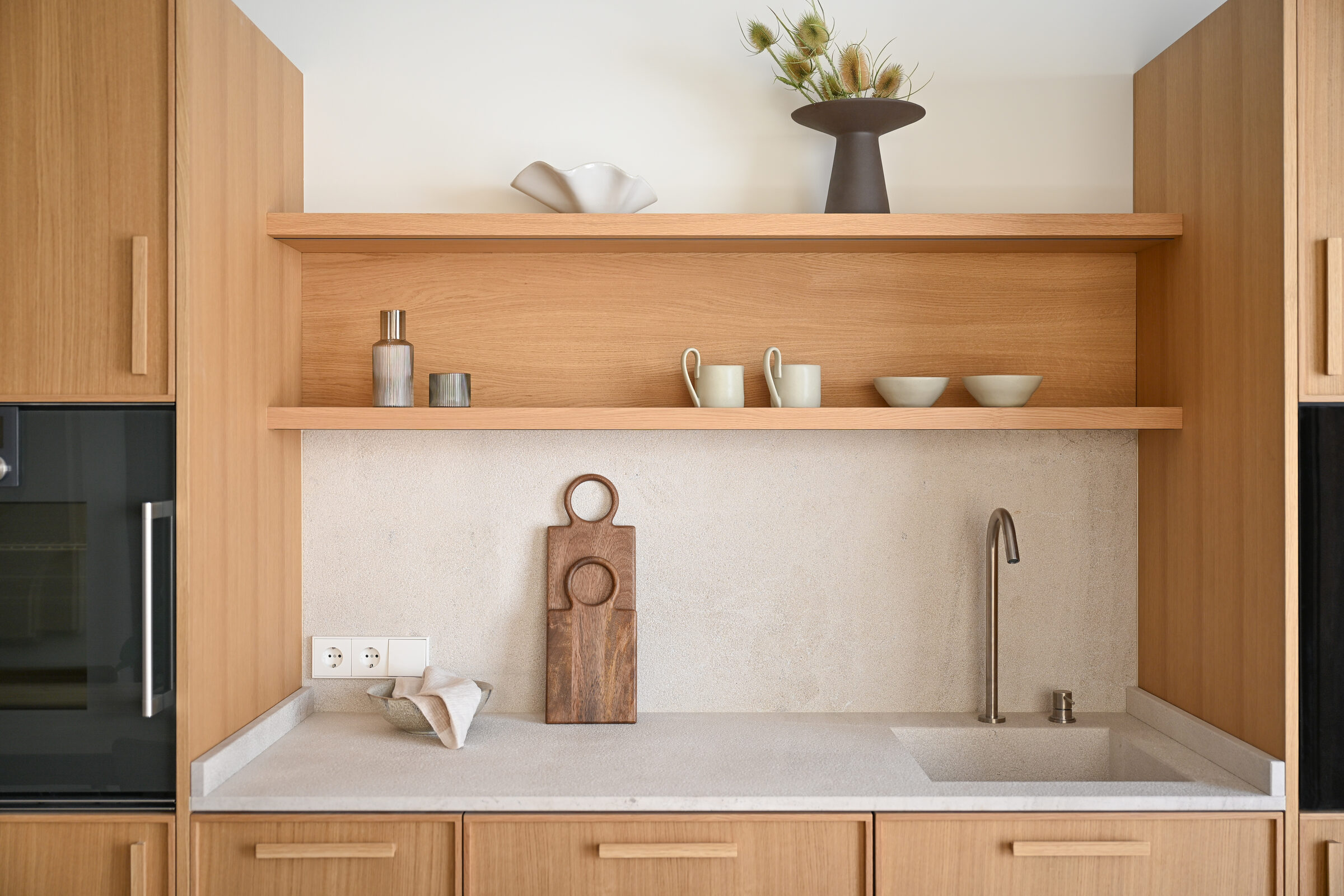 Walnut shelving still life with ceramic vessels and hand-carved cutting boards.