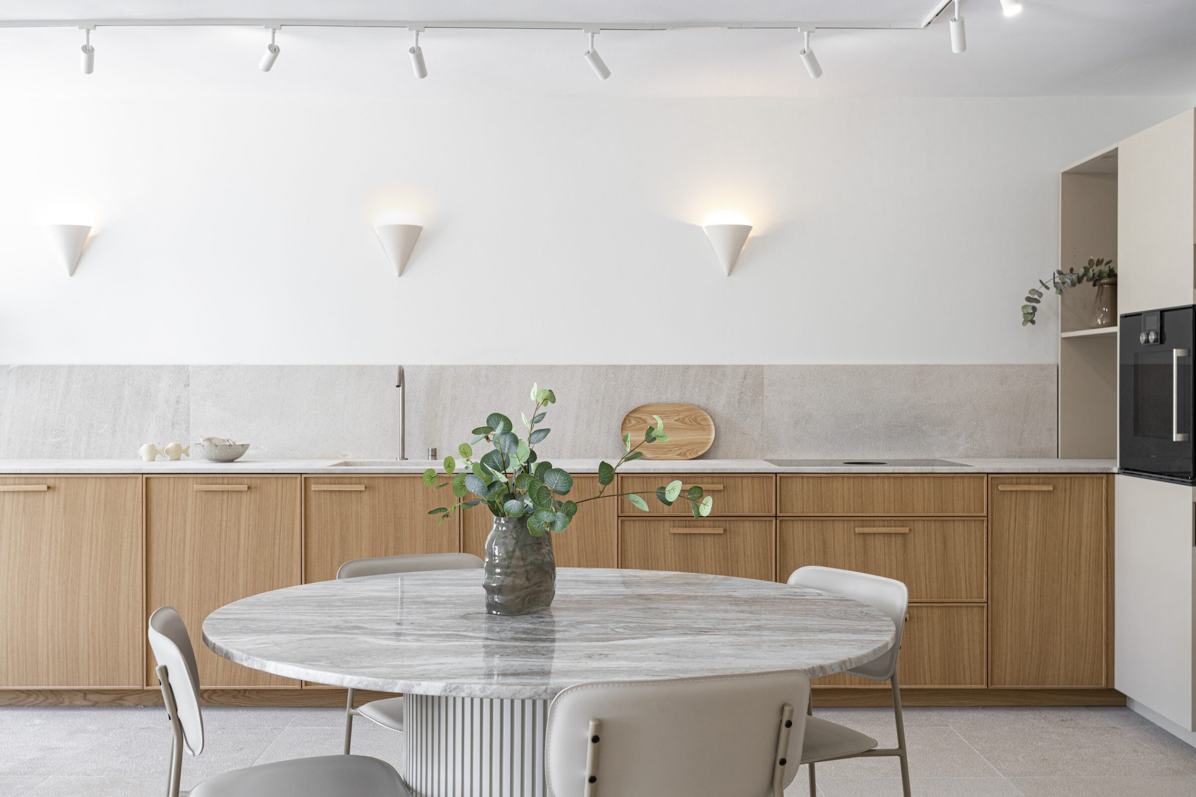 Long walnut kitchen with Binissalem marble countertop and signature ceramic cone wall sconces.