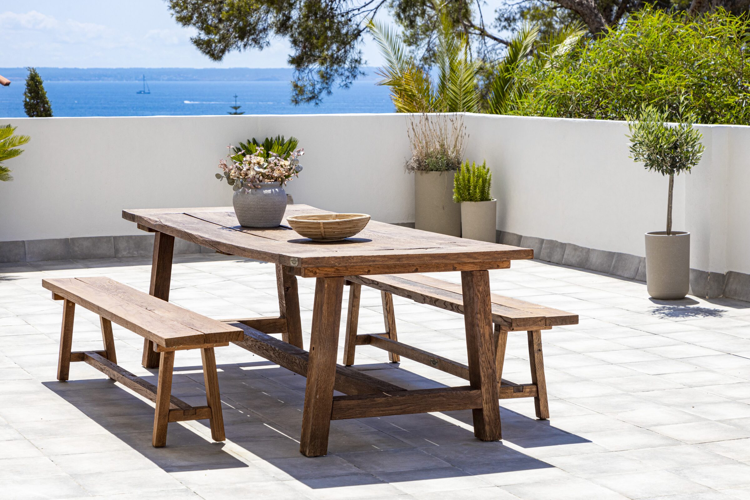 Reclaimed-wood outdoor dining table set against the open Bay of Palma.